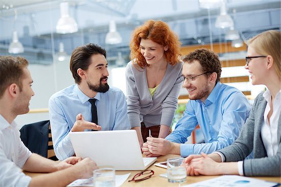 Picture of three men and two women at conference table looking at laptop screen; five-star reviews bring smiles
